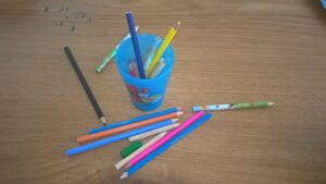 Bezpečnost a ochrana zdraví při práci ve školských zařízeních obrázek ukazuje pastelky na stole a v kelímku.