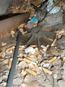 Místo, kde je plno nedopalků, které vzniklo, protože zaměstnanci opakovaně porušují zákaz kouření.